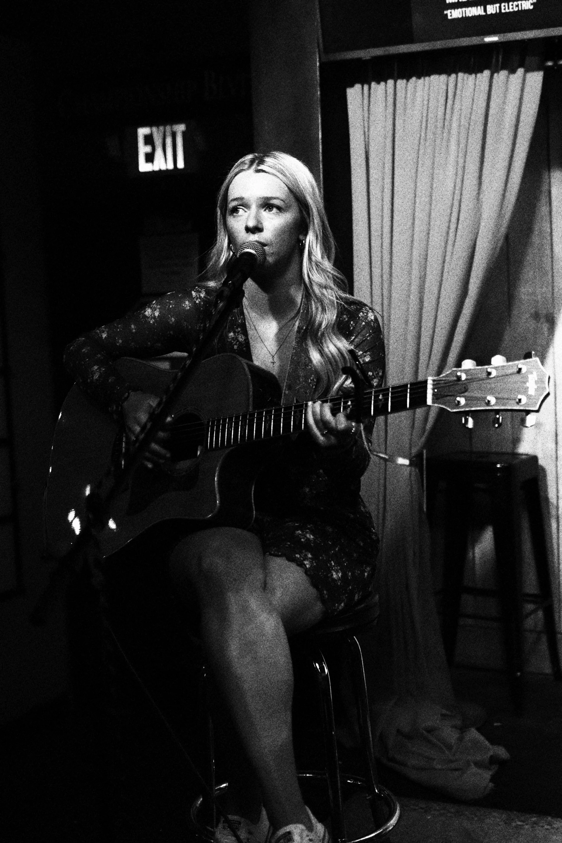 Emily Nelson singing and playing acoustic guitar on stage