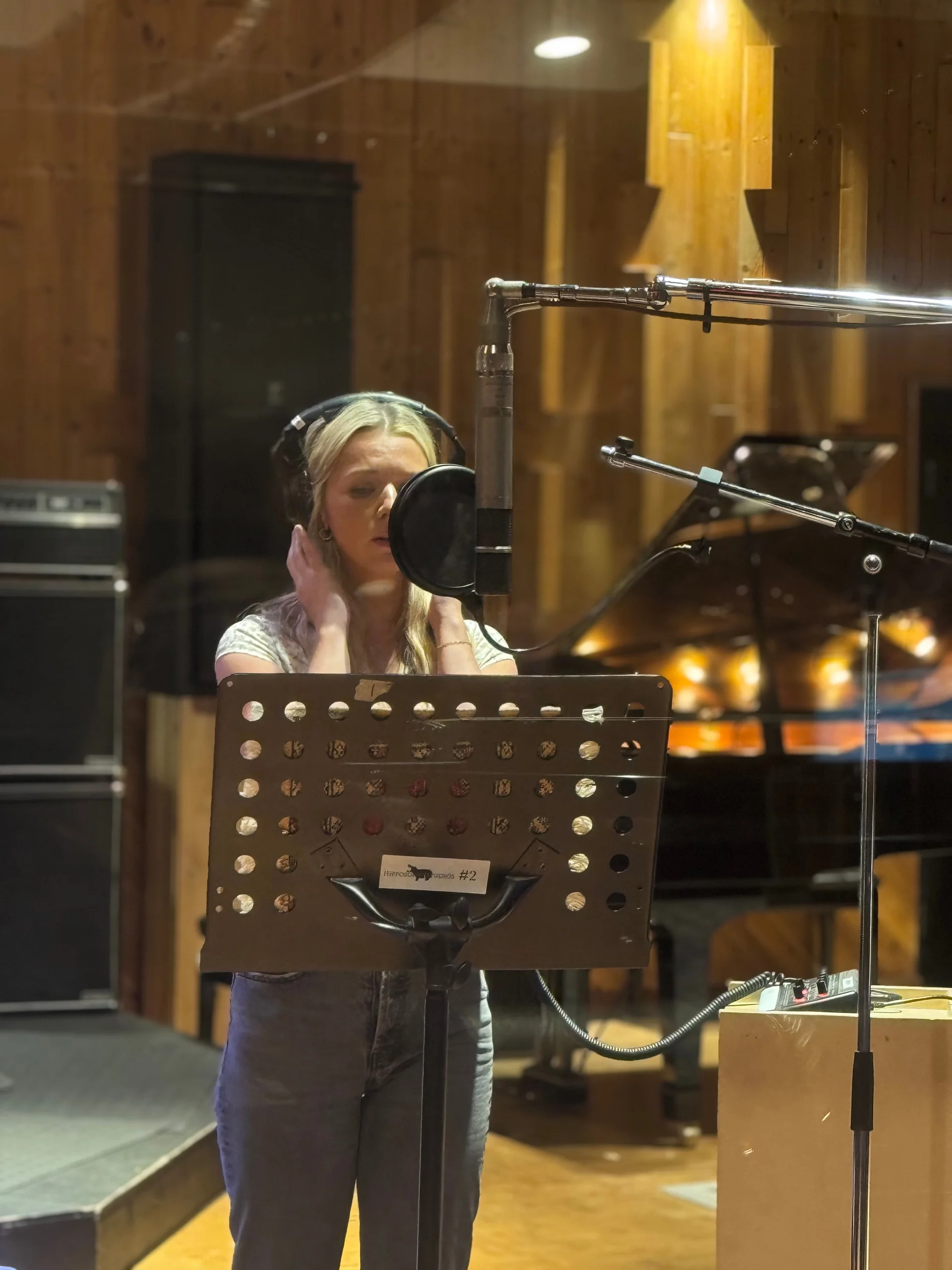 Emily Nelson recording vocals at a studio microphone